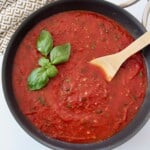 marinara sauce in pan with spoon and fresh basil leaves