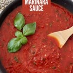marinara sauce in skillet with wooden spoon and basil leaves