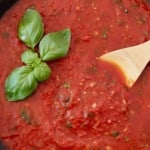 marinara sauce in skillet with wooden spoon and basil leaves