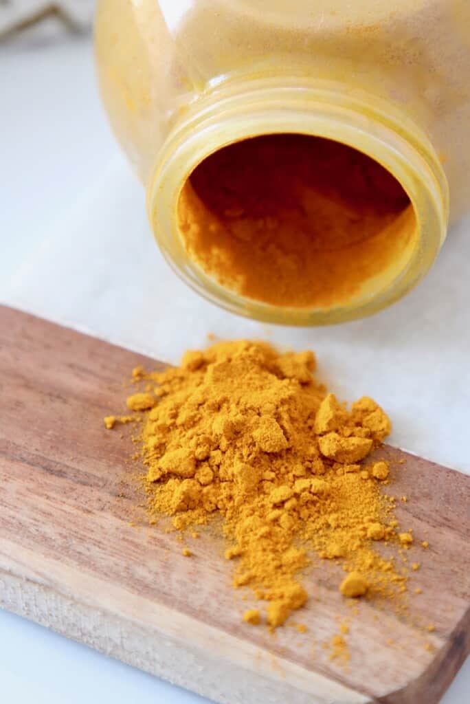 ground turmeric spilling out of jar onto cutting board