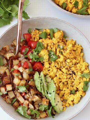 scrambled tofu in bowl with roasted potatoes, tomatoes and avocado