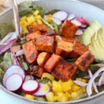 cubes of buffalo tempeh on salad in a bowl