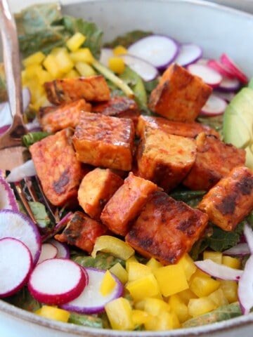 cubes of buffalo tempeh on salad in a bowl