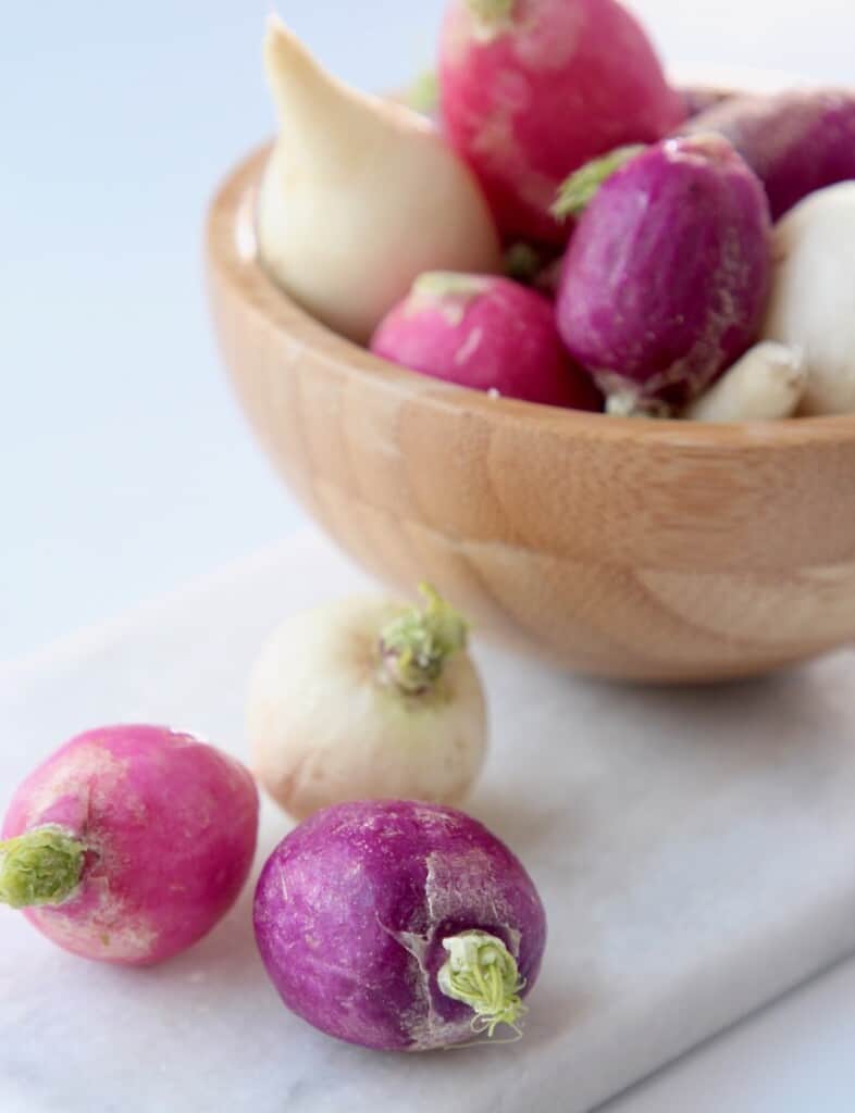 radishes on cutting board and in small wooden bowl