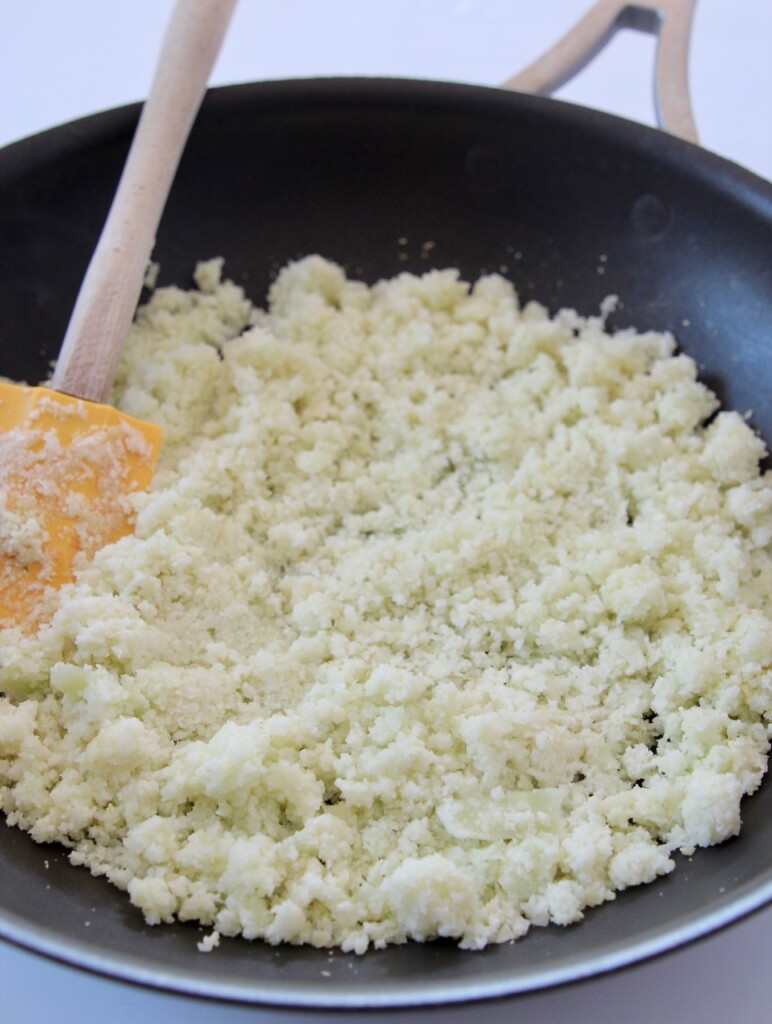 cauliflower rice in a skillet with yellow spatula