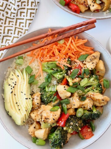 chicken and vegetable teriyaki bowl with sliced avocado and chopsticks