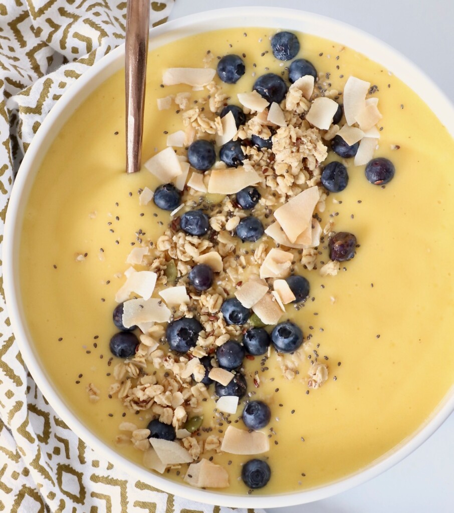 mango smoothie bowl topped with granola and blueberries