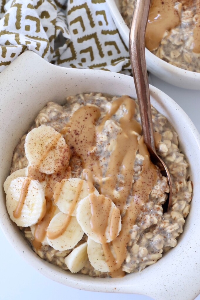 oats in bowl with spoon topped with bananas and peanut butter