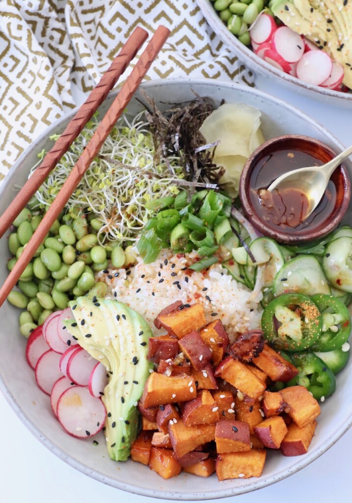 sweet potato poke bowl with chopsticks on the side and sesame sauce in small bowl with spoon