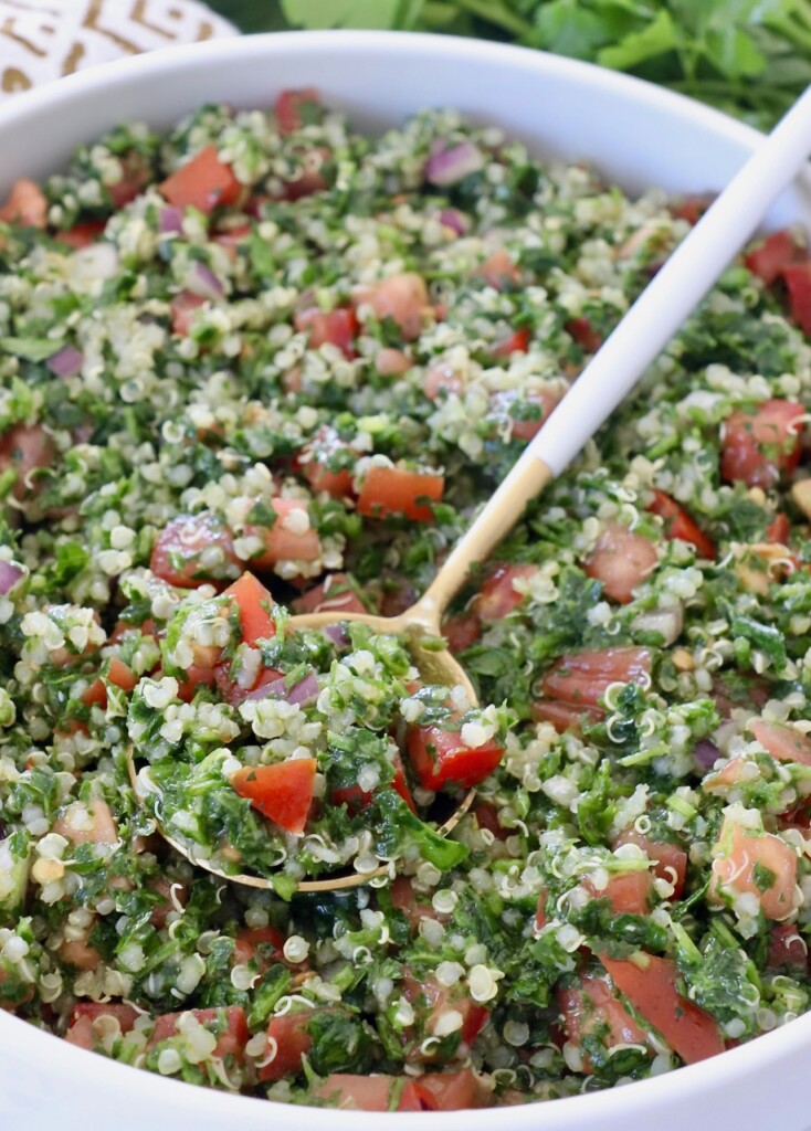 quinoa tabouli salad in bowl with white and gold spoon