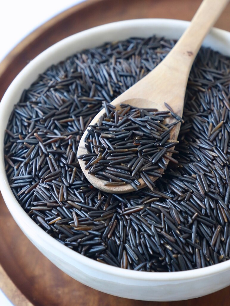 wild rice in white bowl with wooden spoon