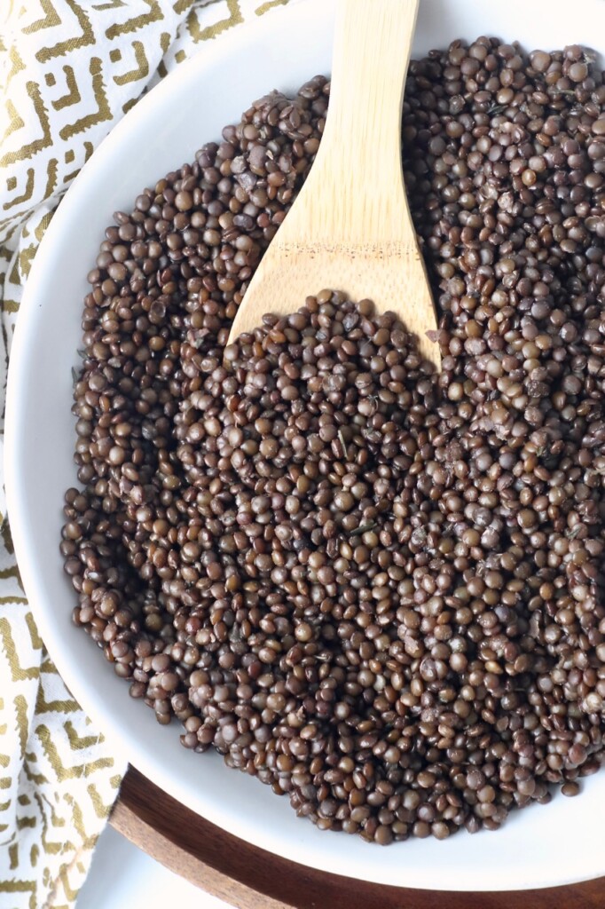 bowl of cooked black lentils with serving spoon