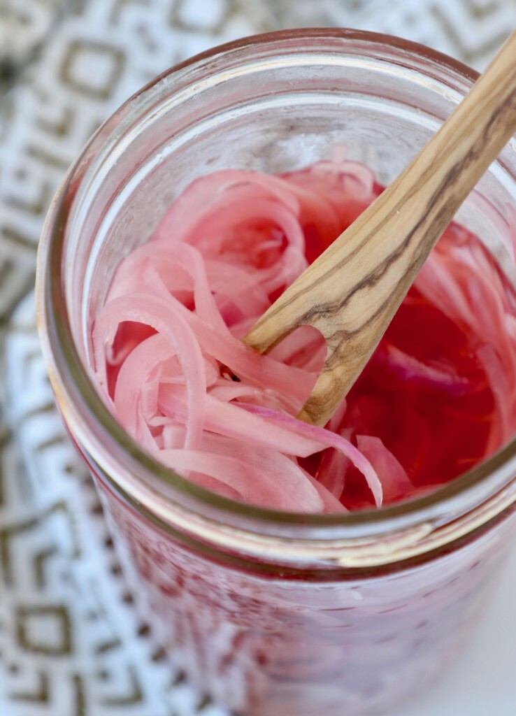 pickled onions in glass mason jar with wooden fork