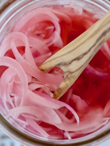 pickled red onions in jar with wooden fork