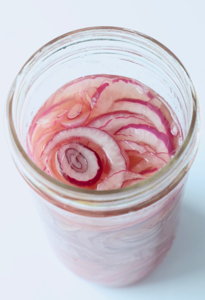 thinly sliced onions in pickling liquid mason jar