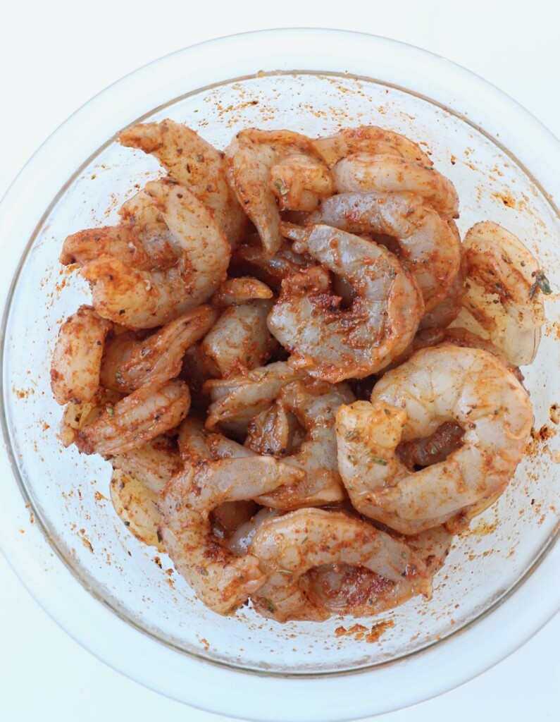 raw shrimp with oil and seasoning in glass bowl