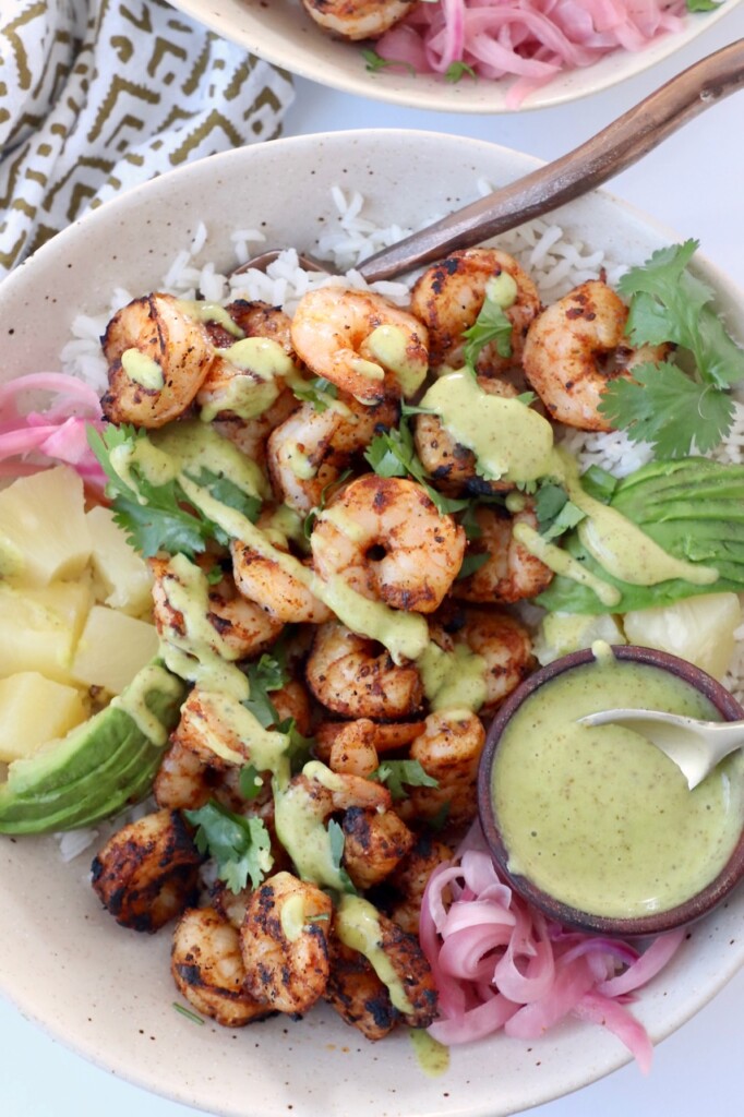 blackened shrimp in bowl with honey lime dressing and diced pineapple