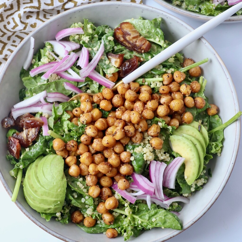 roasted chickpea salad in bowl topped with sliced onion and avocado