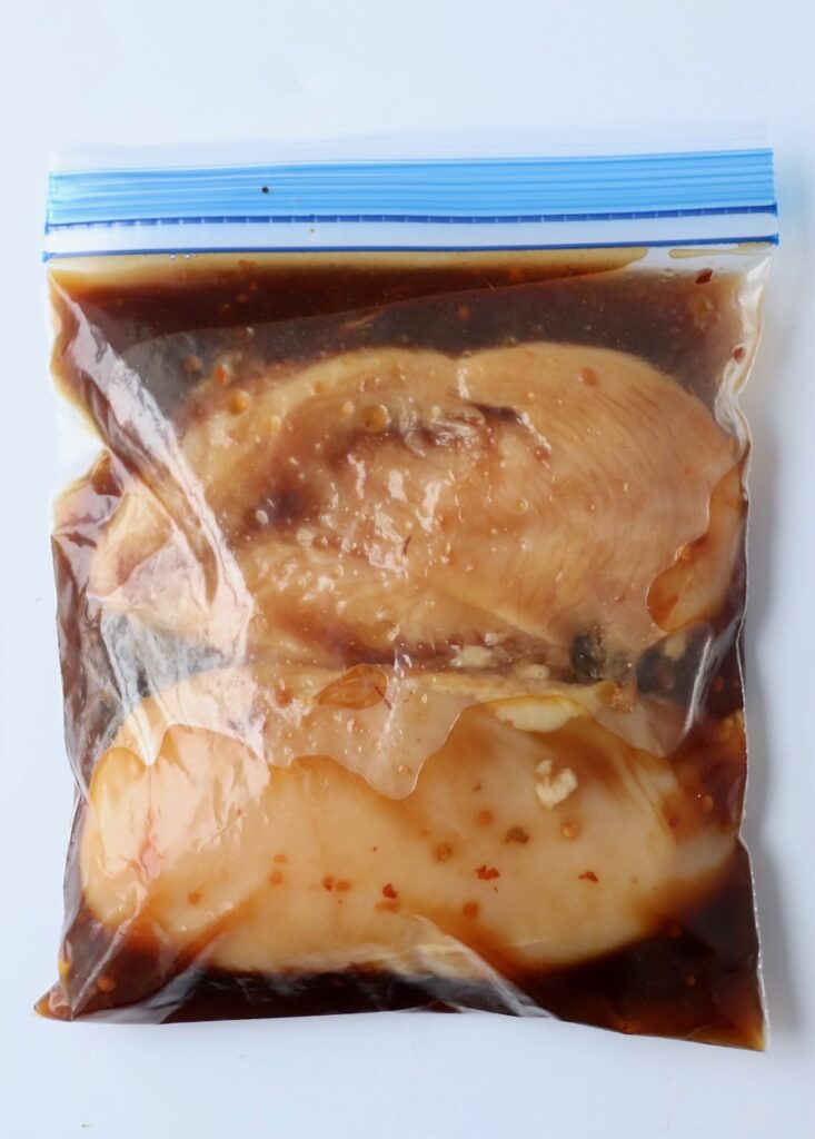 chicken breasts in marinade in plastic zipper bag