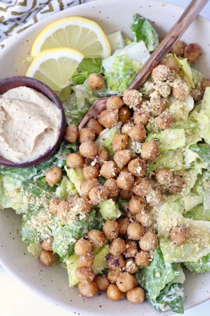 caesar salad in bowl with fork topped with chickpeas