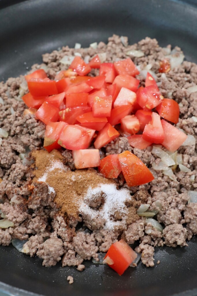 cooked ground beef in skillet with seasonings and tomatoes