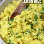 lemon rice in bowl with wooden spoon with fresh herbs