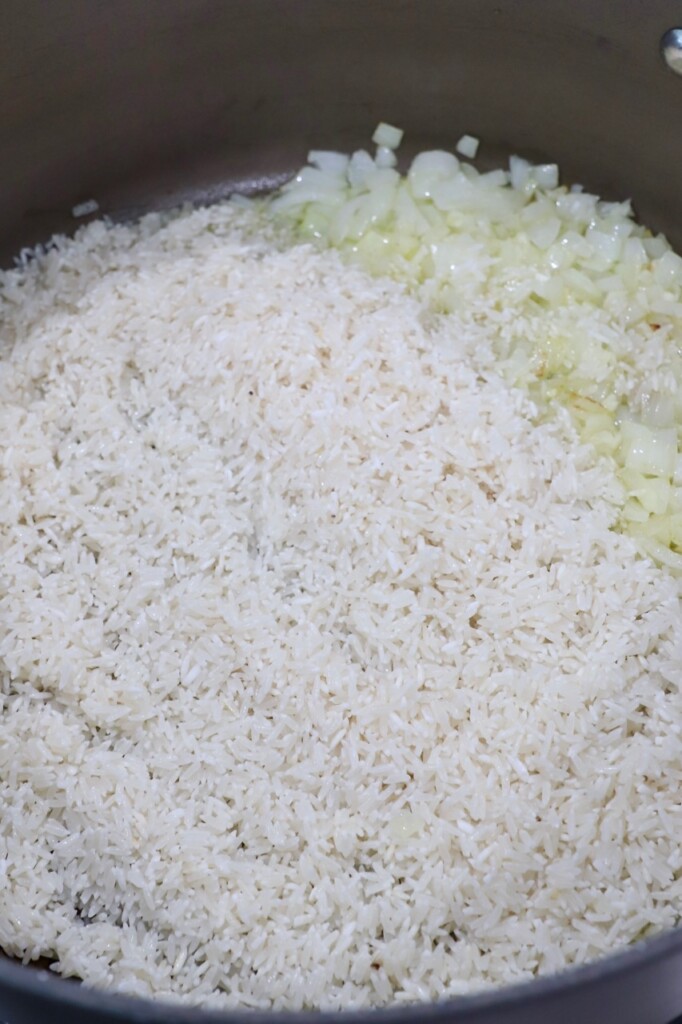white rice in skillet with diced onions and garlic