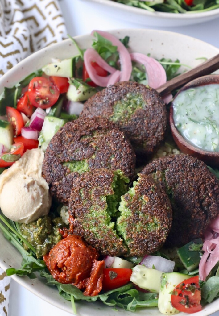 fried falafel patties in bowl with vegetables and sauce