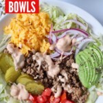 ground beef in bowl with veggies, shredded cheese and burger sauce drizzled on top