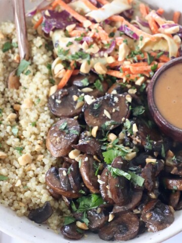 cooked mushrooms in bowl with cooked quinoa, coleslaw and peanut sauce